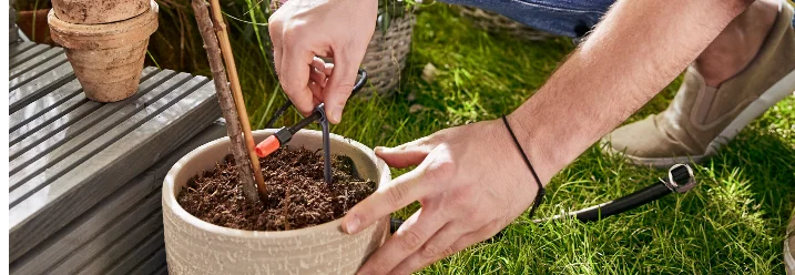 Person bringt Schlauch an Blumentopf an
